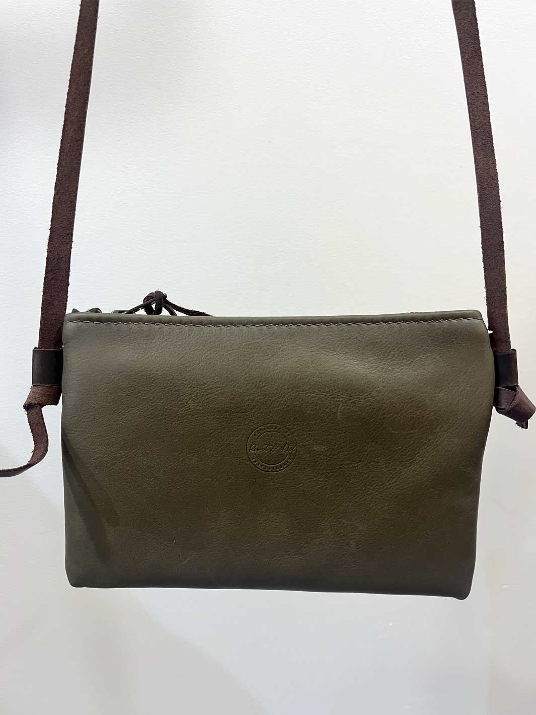 An olive green leather crossbody bag with a dark brown shoulder strap, shown against a plain white background.