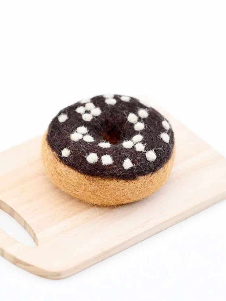Felted donut toy on a wooden board with a white background