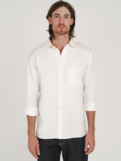 Man wearing a white hemp button-up shirt with plastic-free buttons against a plain background