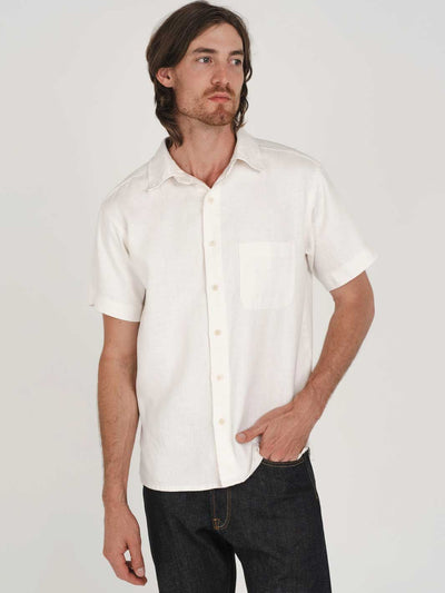Man wearing a white short-sleeve hemp shirt against a plain background