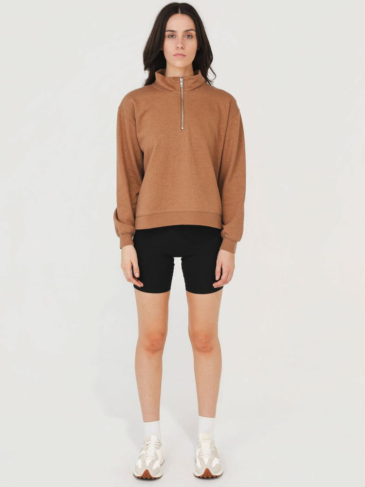 Woman wearing a brown sweatshirt and black shorts on a white background