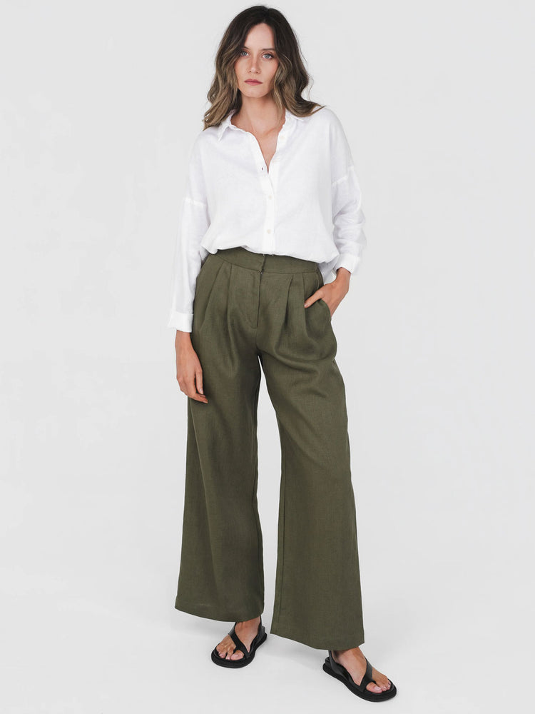 Woman wearing a white shirt and green wide-leg pants on a white background