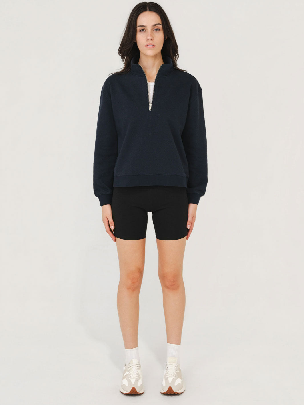Person wearing a navy blue sweatshirt and black shorts on a white background