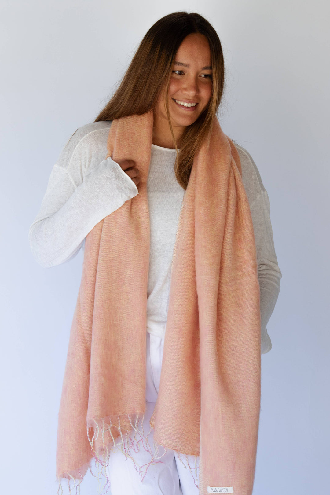 Woman wearing a light pink scarf against a white background