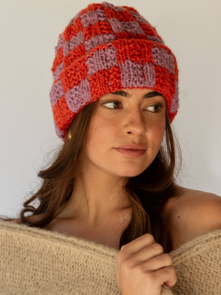 Woman wearing a red and purple knitted hat against a plain background