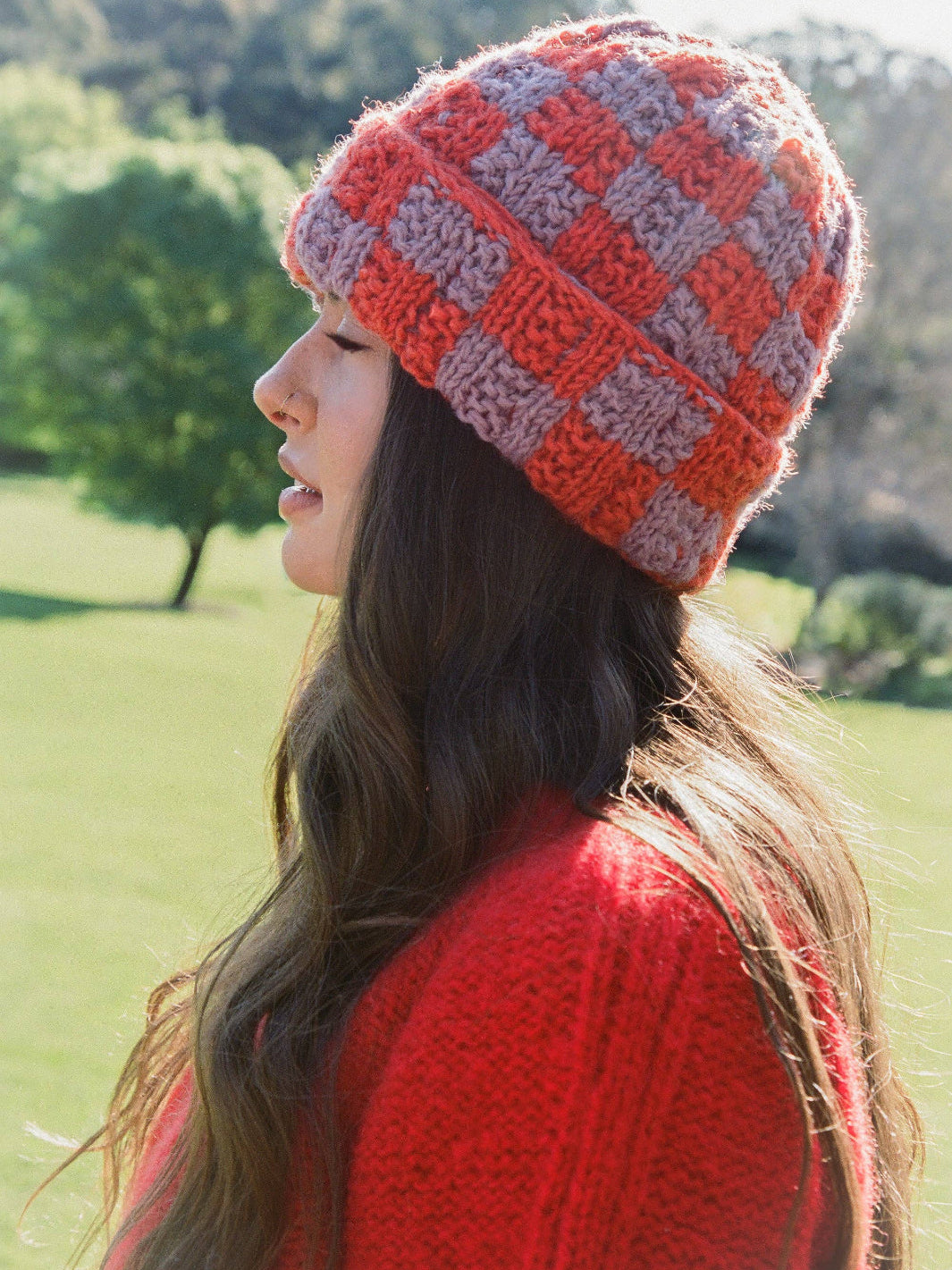 Woman wearing a red and gray checkered knit hat outdoors