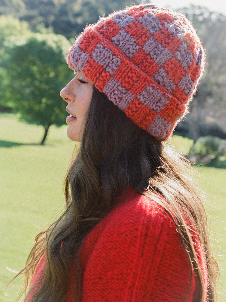 Woman wearing a red and gray checkered knit hat outdoors