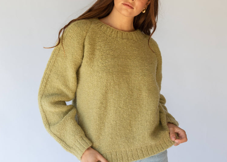 Person wearing a green sweater against a white background