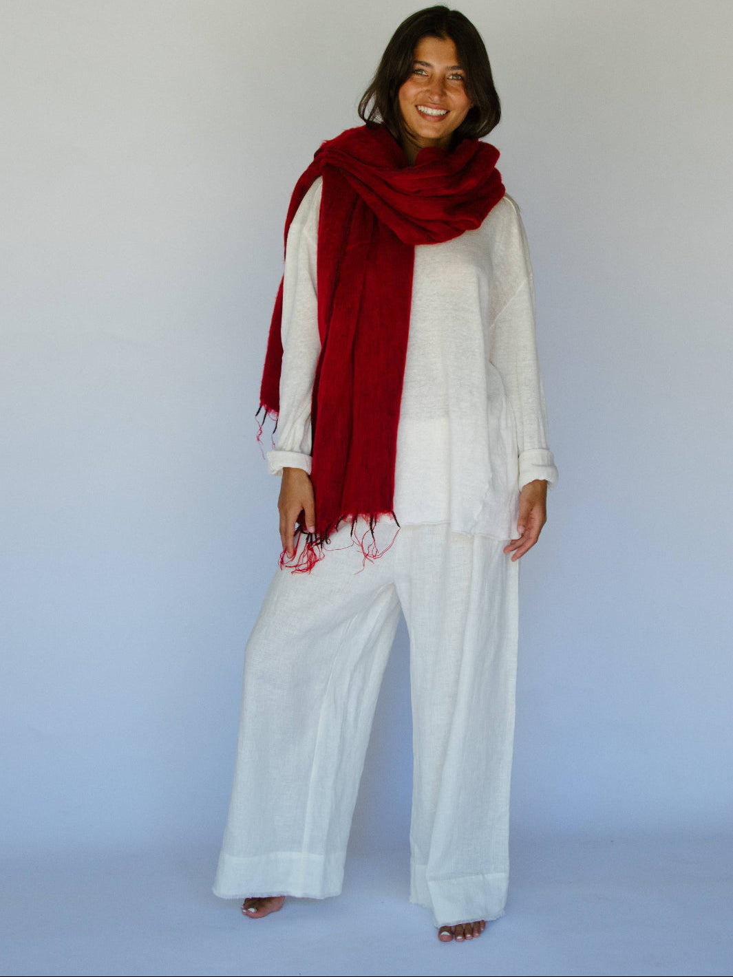 Woman wearing a red scarf and white outfit against a plain background