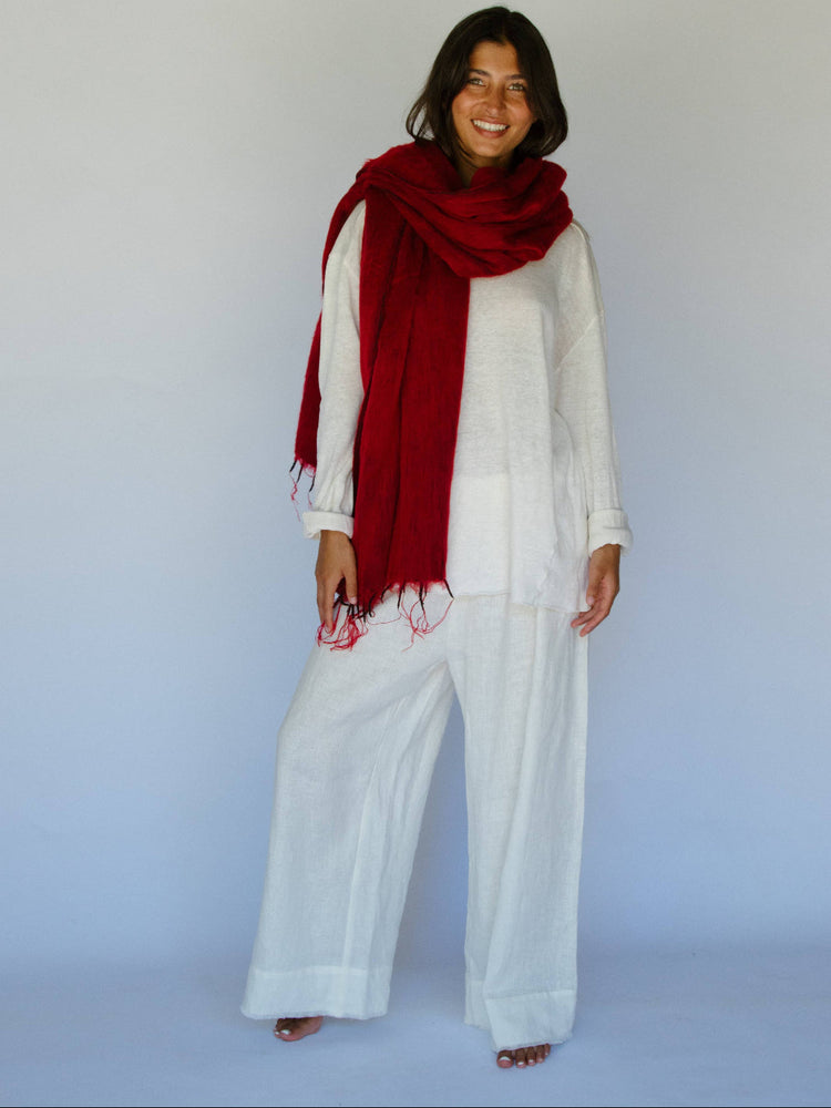 Woman wearing a red scarf and white outfit against a plain background