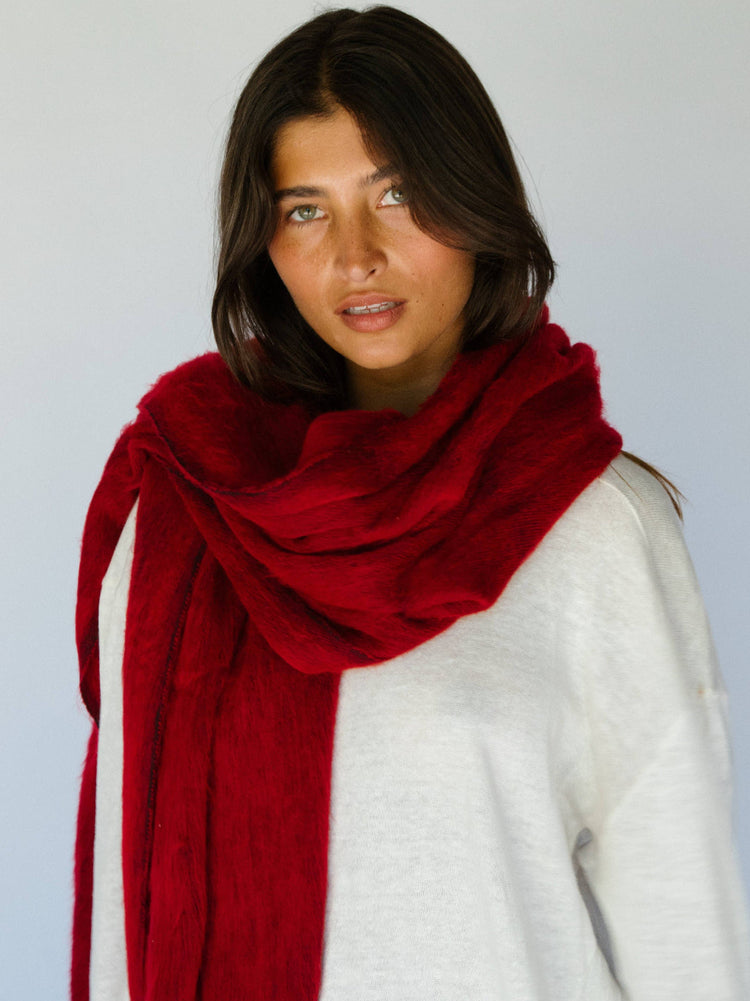 Woman wearing a red scarf and white sweater against a plain background