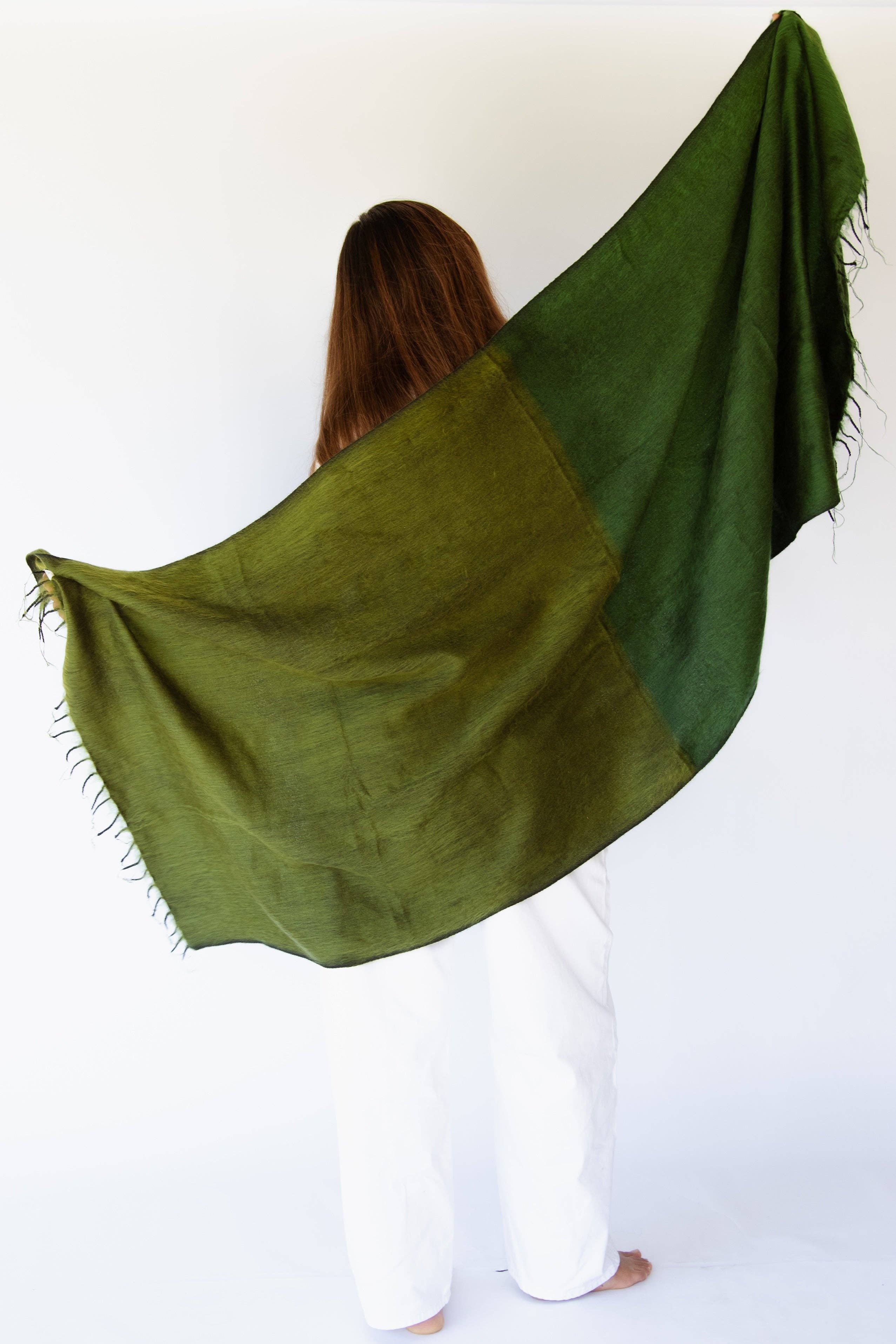 Person wearing a green shawl over their shoulders against a white background