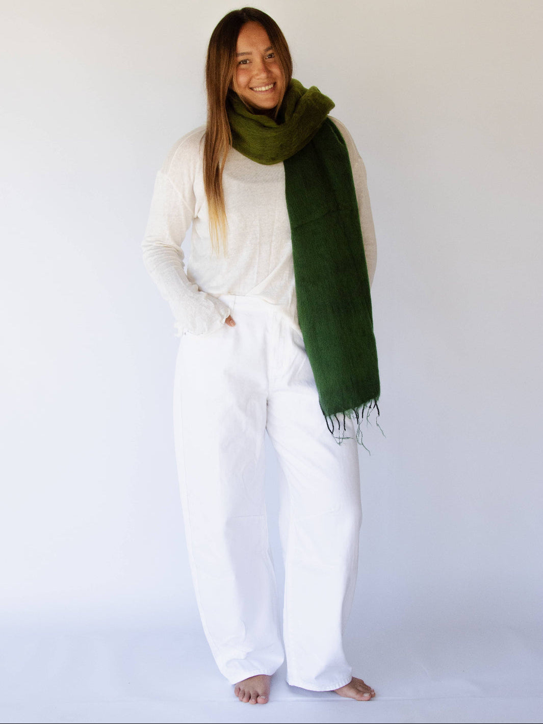Woman wearing a green scarf and white outfit against a white background