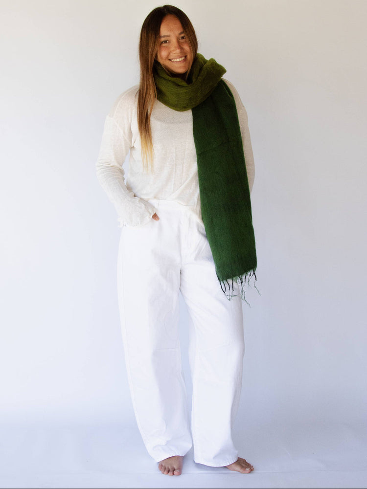 Woman wearing a green scarf and white outfit against a white background