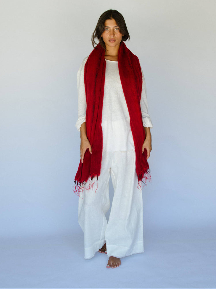 Person wearing a red scarf and white outfit on a plain background