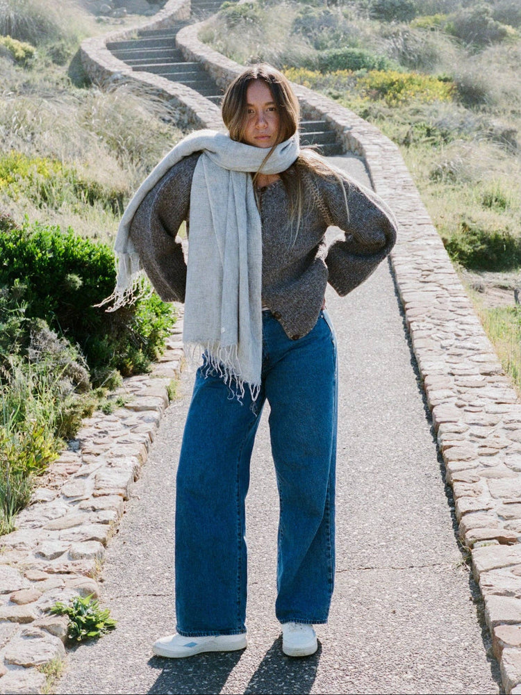Woman walking on a path with a scarf and sweater in a natural setting