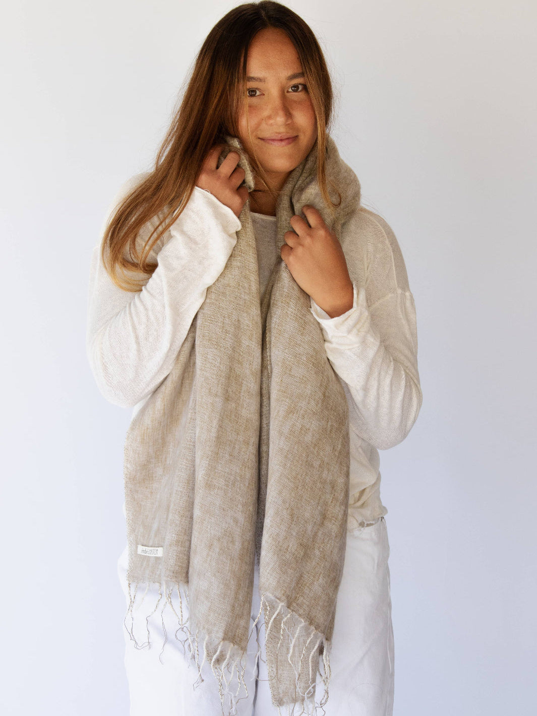 Woman wearing a beige scarf against a white background