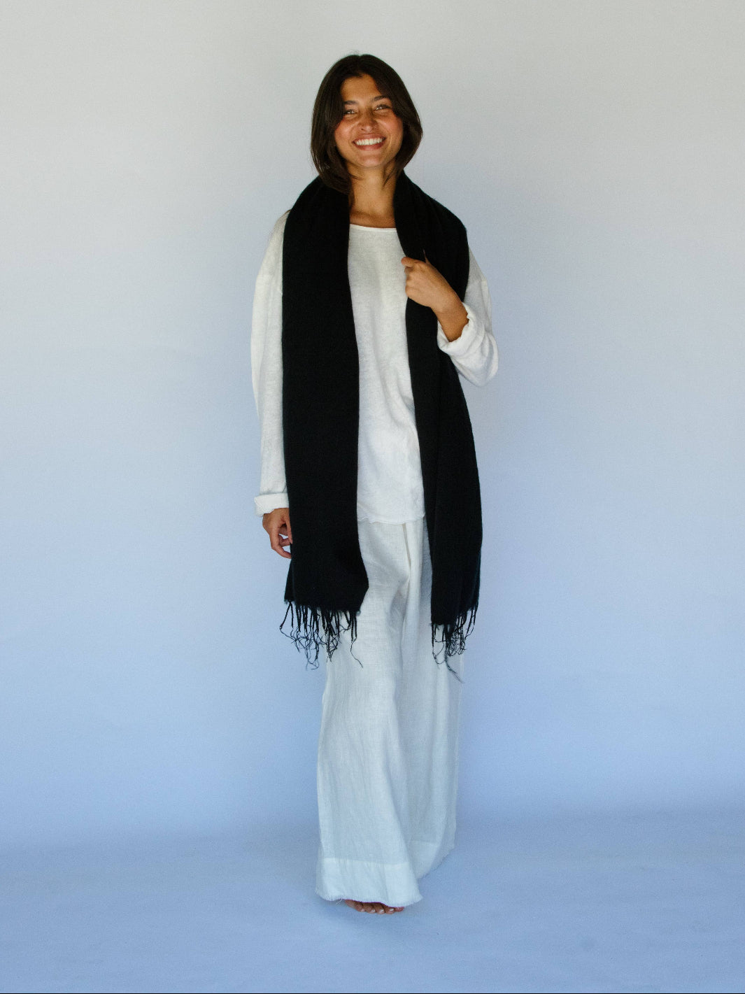 Woman wearing a black scarf and white outfit against a light blue background