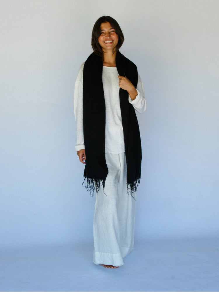 Woman wearing a black scarf and white outfit against a light blue background