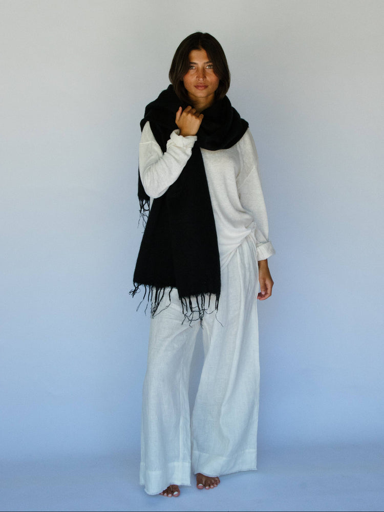 Person wearing a black scarf and white outfit against a light blue background