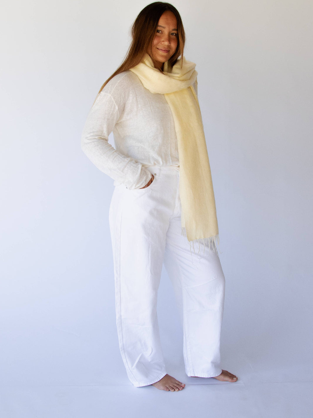 Person wearing a yellow scarf and white outfit on a plain background