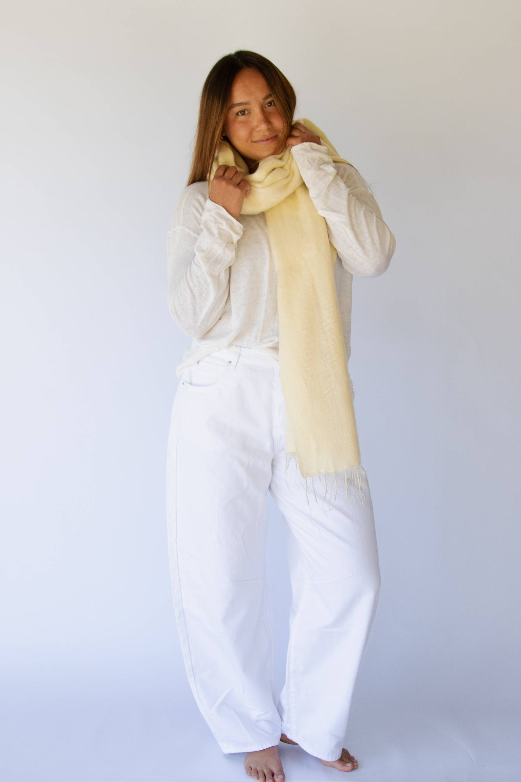 Person wearing a yellow coloured scarf and white outfit against a plain background