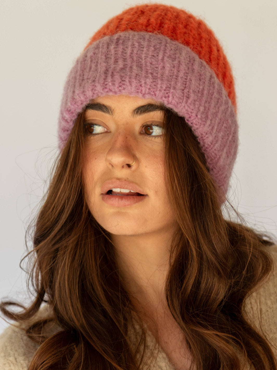 Woman wearing a colorful knit beanie against a plain background