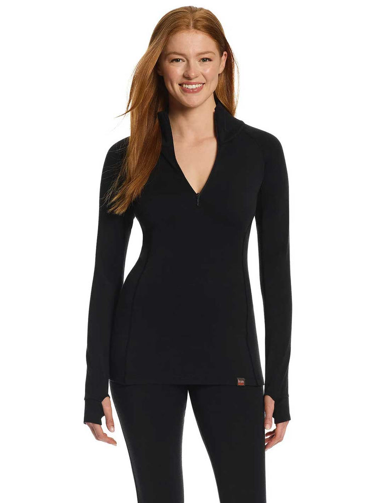 A smiling woman with long red hair models a black long-sleeve quarter-zip pullover thermal top with zip and matching black leggings against a plain white background.