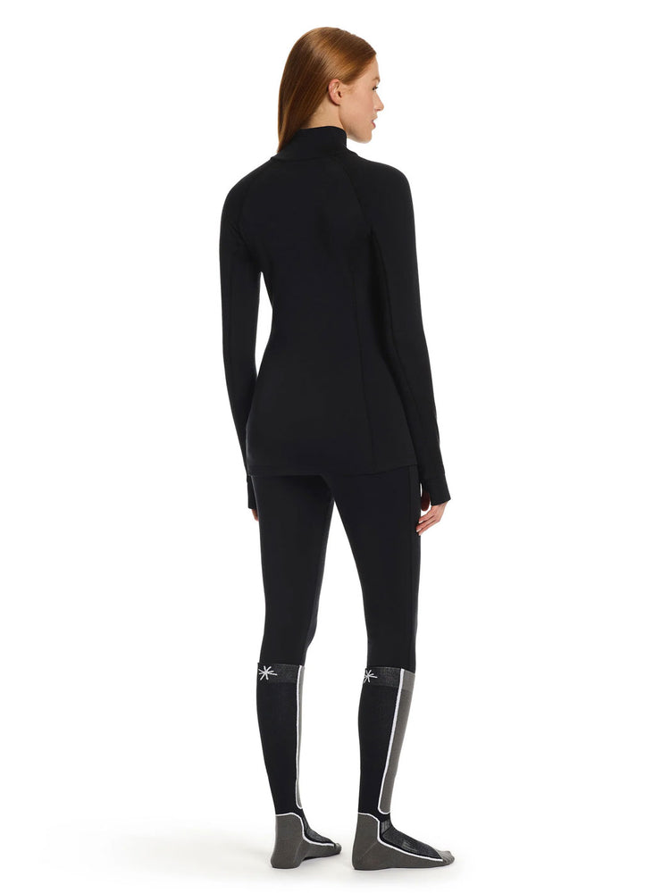 A woman shown from the back wearing a black long-sleeve mock-neck top and matching black leggings with white side stripes and black-and-white booties, against a plain white studio background.