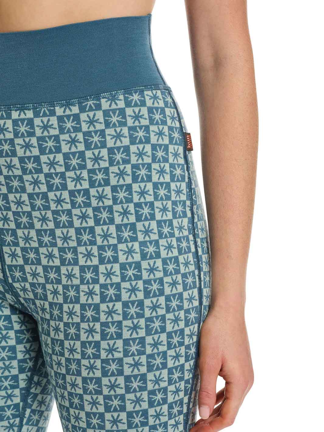 Close-up of a person wearing high-waisted leggings with a blue and white geometric star pattern and a solid blue waistband.