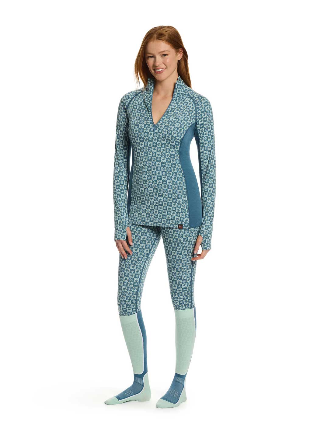 A woman modeling a matching two-piece athletic set with a blue and white geometric pattern, featuring a long-sleeve quarter-zip top and matching leggings, paired with light blue and blue socks, on a white background.