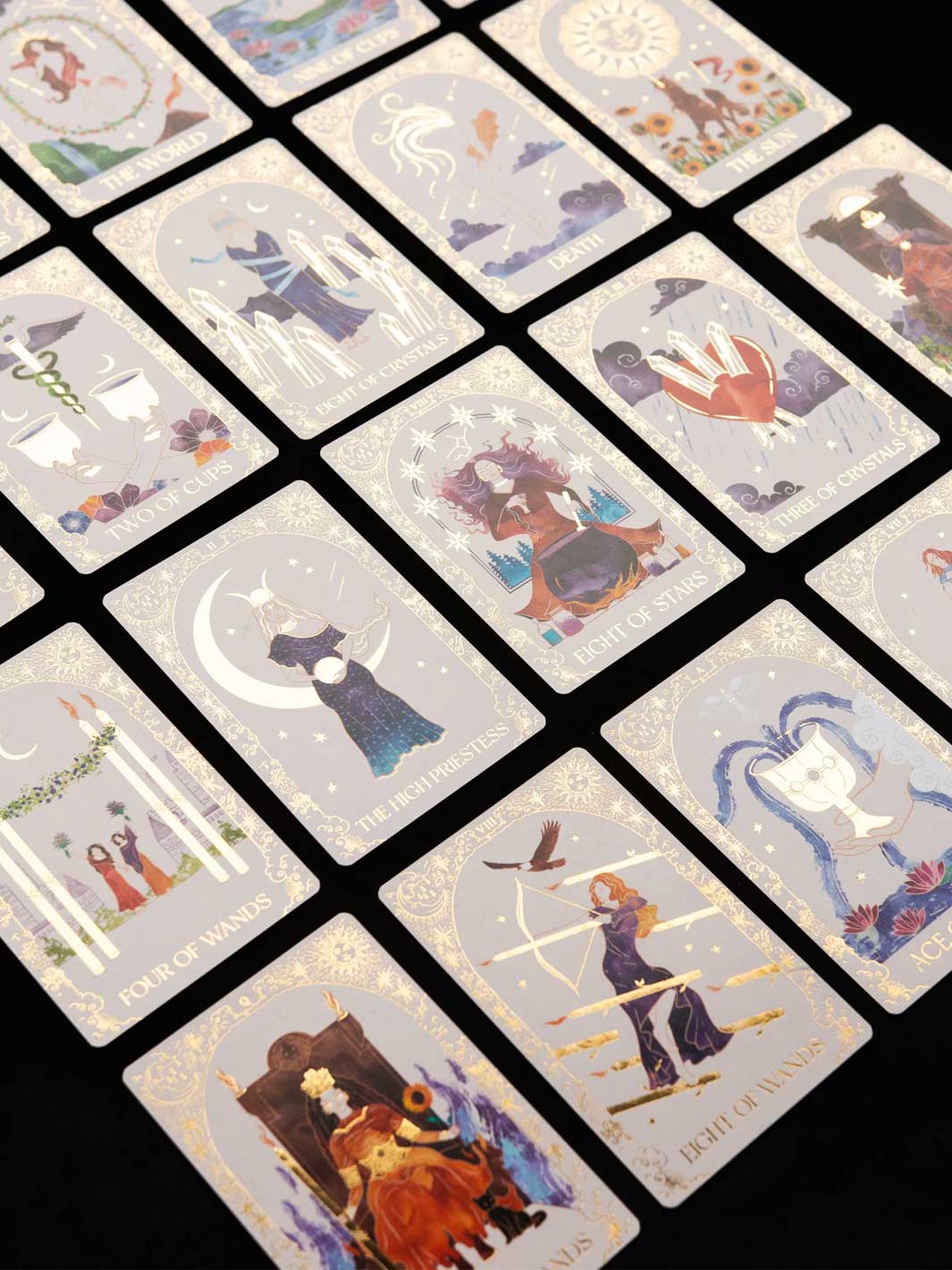A set of illustrated tarot cards arranged in a grid on a black background. The cards feature soft pastel artwork with celestial and mystical imagery, including moons, birds, hands, and figures in flowing garments.