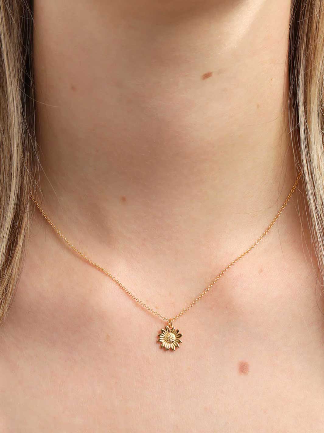Gold necklace with a small pendant on a person's neck