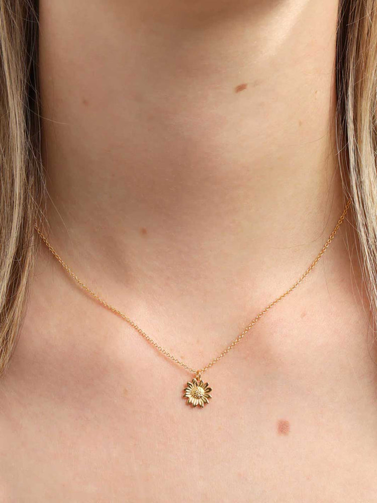 Gold necklace with a small pendant on a person's neck