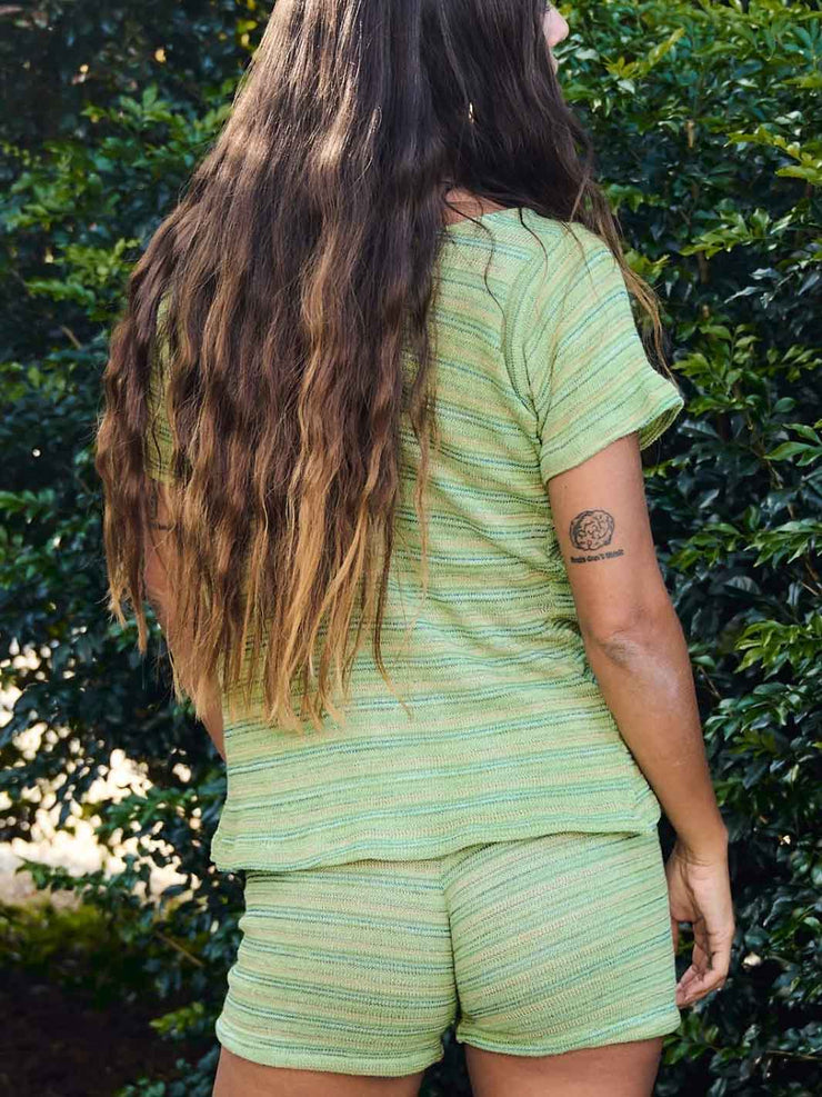 Woman wearing a green striped baby tee in hand dyed cotton. Made in Australia