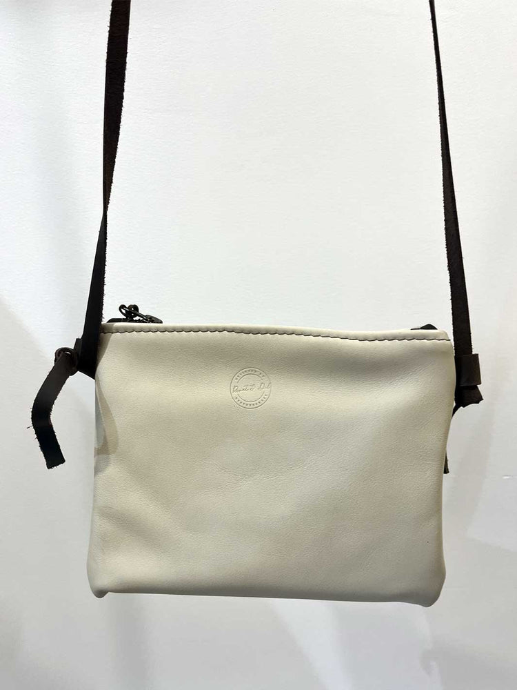 A small off-white leather crossbody bag with a dark brown shoulder strap and a debossed circular logo on the front, shown against a plain white background.