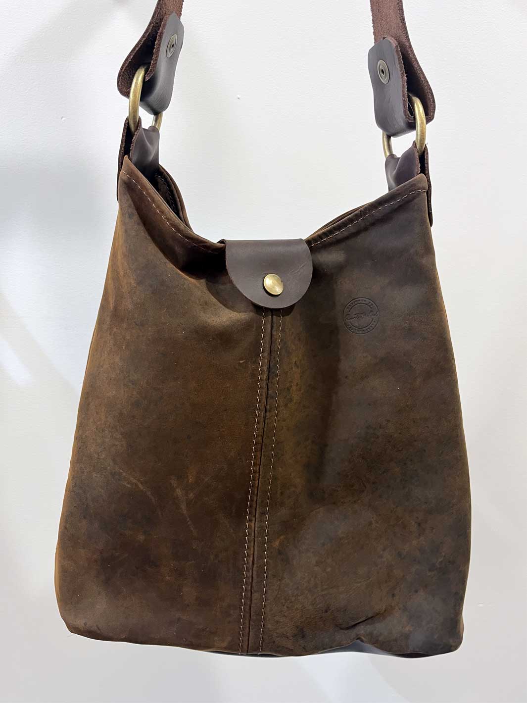 A dark brown distressed leather hobo tote shoulder bag with a front snap closure and a single strap, shown against a plain white background.