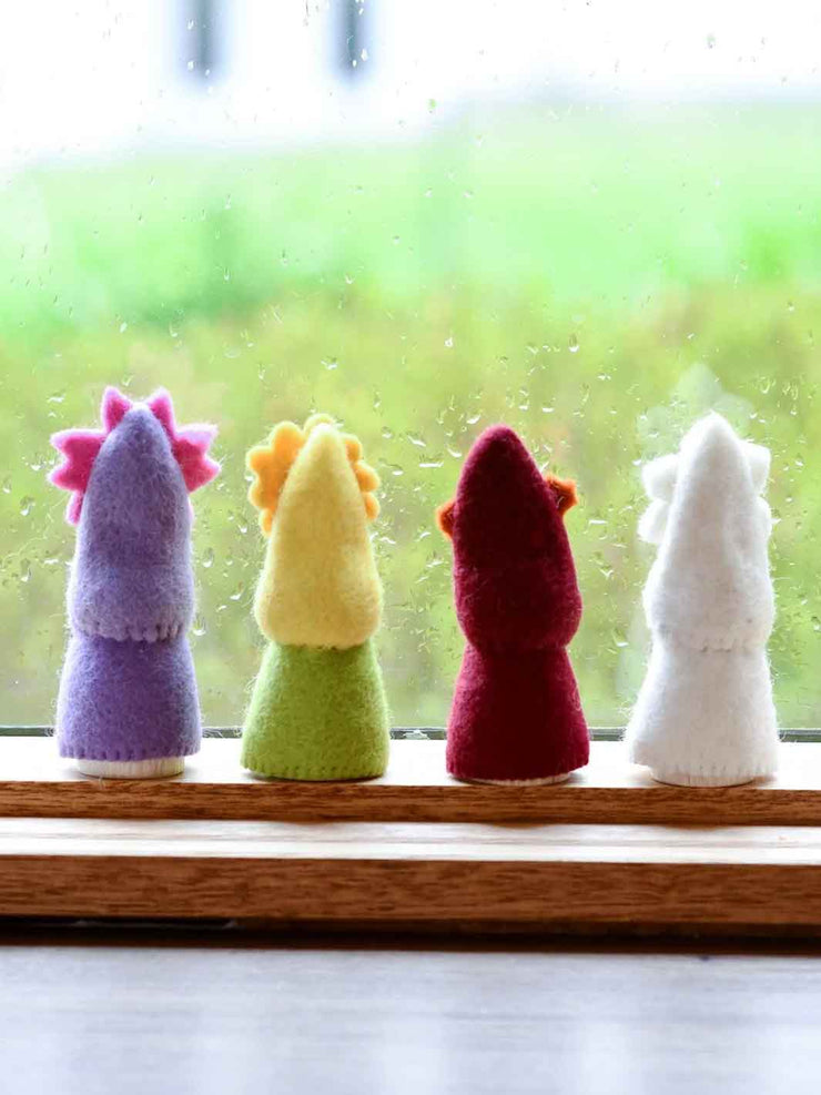Four colorful felted animal figurines on a windowsill with a blurred green outdoor background.