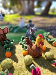 Felted garden scene with chickens, rabbits, cat and vegetables on a grassy background