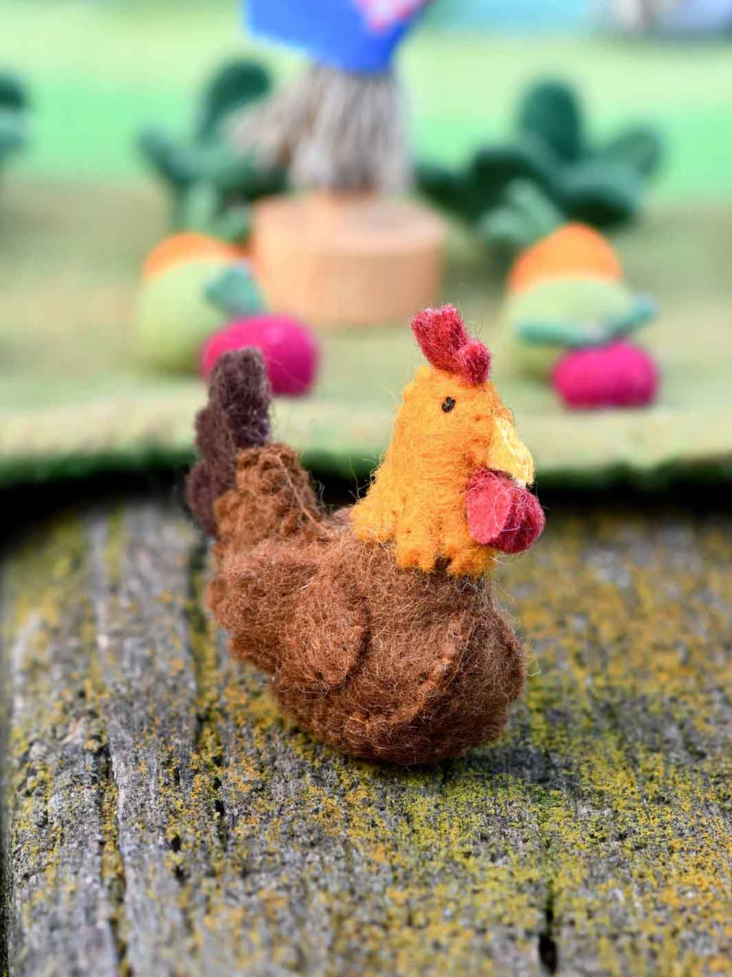 Felt chicken toy on a textured surface with blurred background
