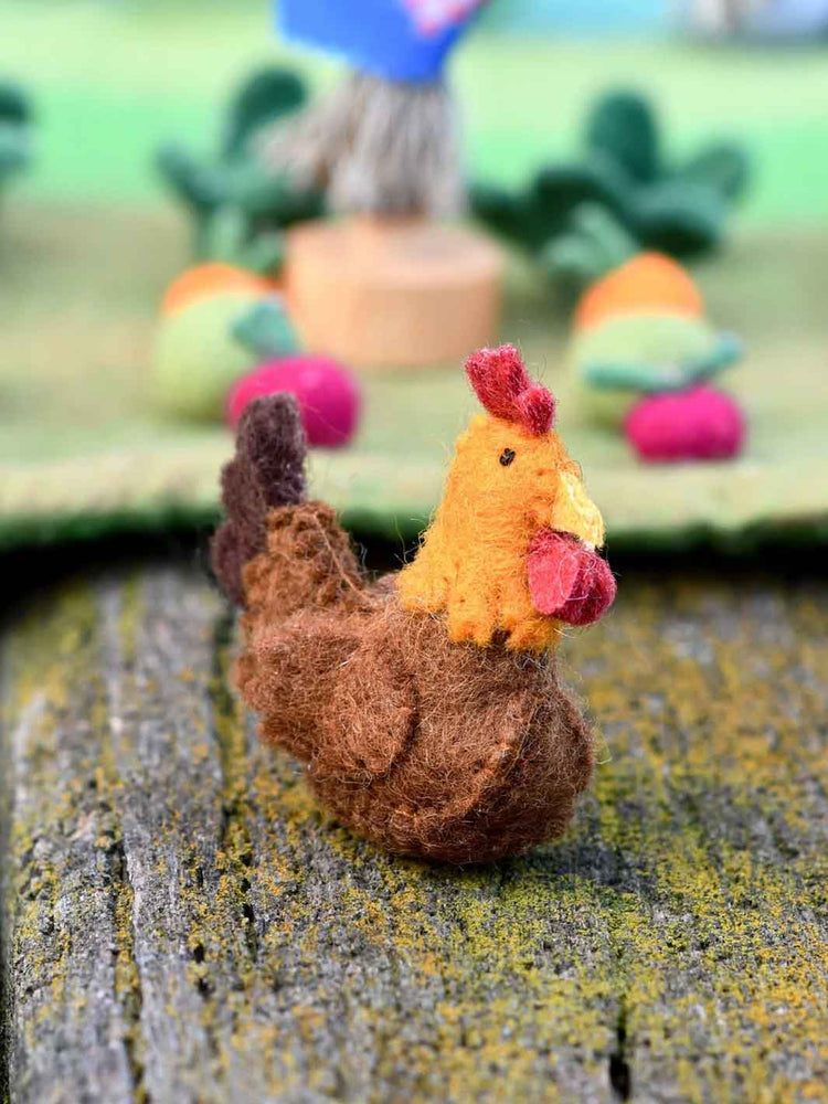 Felt chicken toy on a textured surface with blurred background