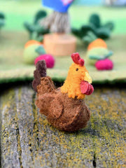 Felt chicken toy on a textured surface with blurred background