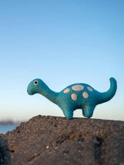 Blue toy dinosaur on a rock with a clear blue sky background
