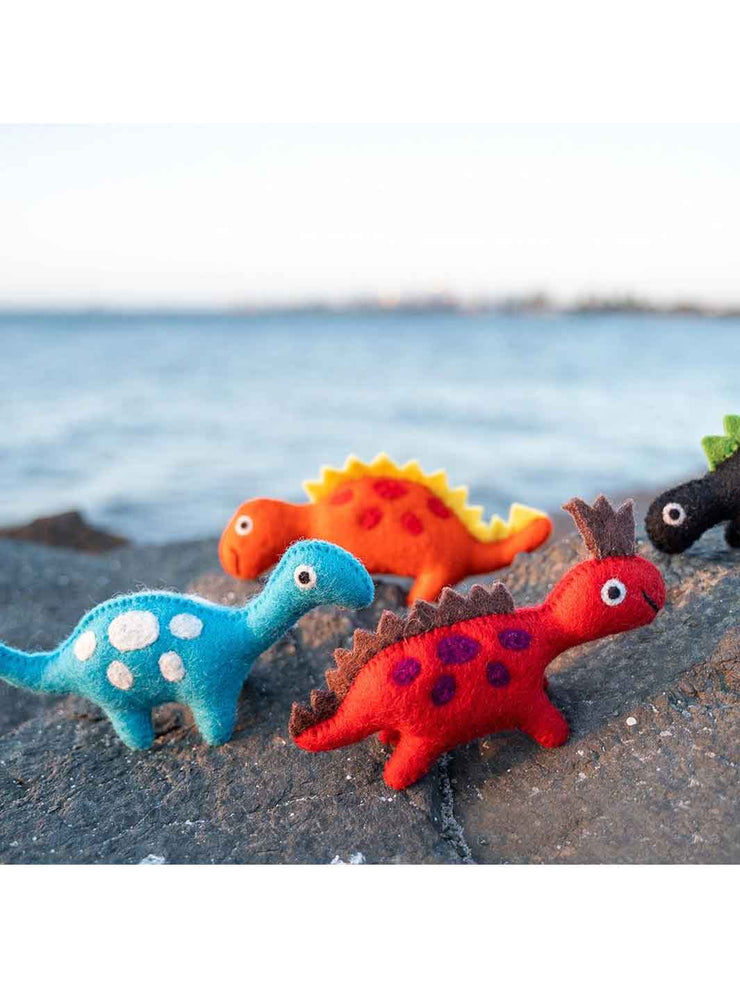 Colorful dinosaur toys on a beach with water in the background