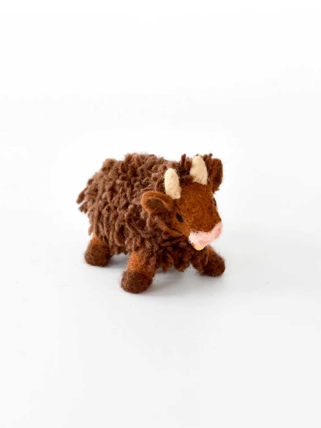 A small brown plush wool felt toy shaped like a Highland cow or yoke, with cream-coloured horns and a pink nose, photographed on a clean white background.