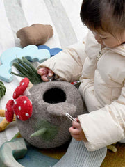 Child playing with a felted toy  resembling a rabbit hole.