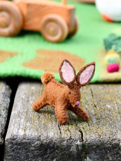 Felt bunny toy on a wooden surface with a blurred background