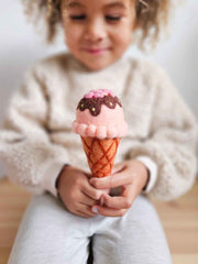 Child holding a pink ice cream cone toy with sprinkles