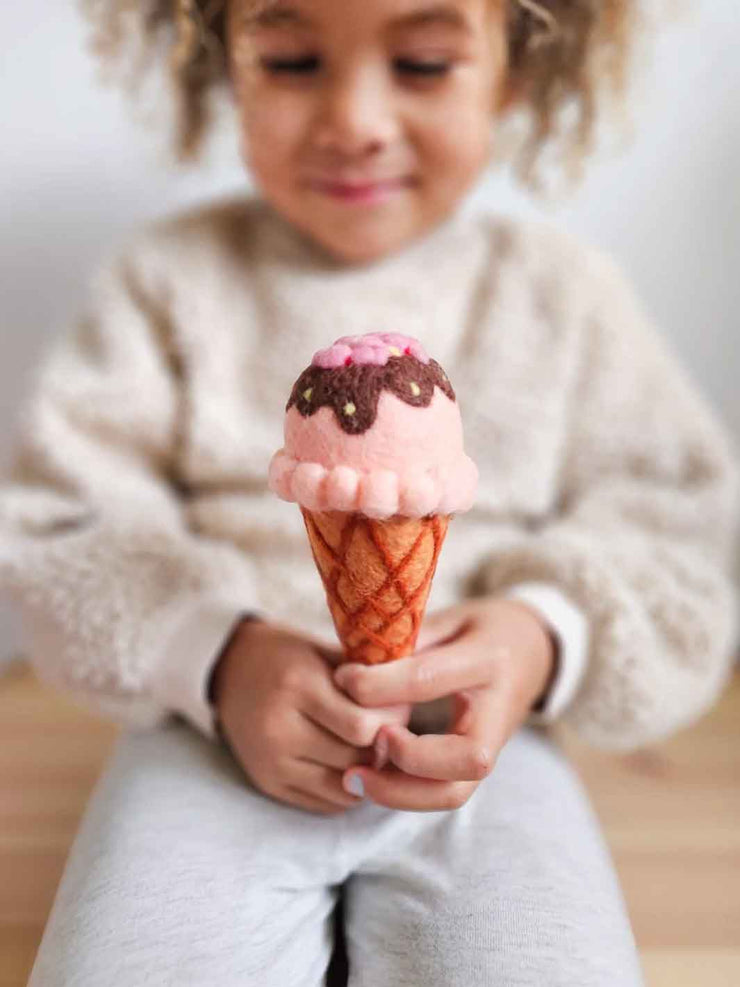 Child holding a pink ice cream cone toy with sprinkles