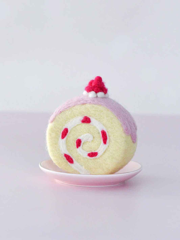 Felt toy resembling a swiss roll with pink and white swirl on a light gray background